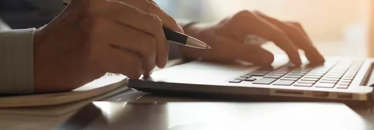  Imagen de unas manos y un ordenador como si estuviese trabajando o tecleando.
