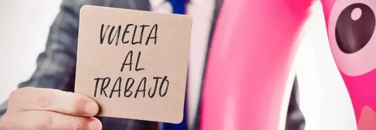 Hombre en traje aguantando un post-it que pone ‘vuelta al trabajo’