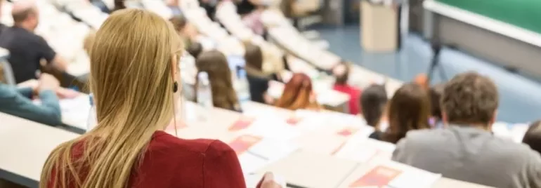 Jóvenes en un entorno de formación, comparando opciones de carrera, con una pizarra o portátil con información sobre FP y universidad