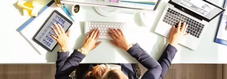 Persona trabajando con múltiples dispositivos en un escritorio.