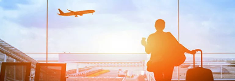 Persona en aeropuerto observando un avión despegar.