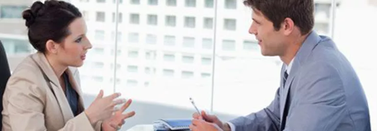 Dos personas hablando en una sala de juntas moderna.