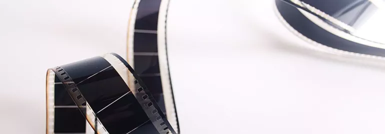 Cinta de película de cine enrollada sobre fondo blanco.