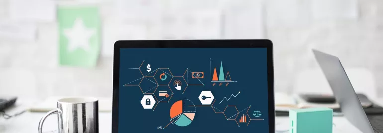 Portátil con gráficos y diagramas en pantalla sobre mesa de trabajo.