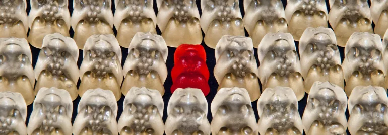 Dulces de goma, uno rojo entre muchos blancos.