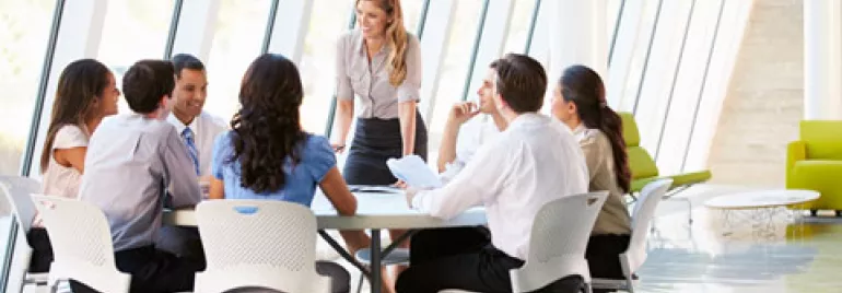 Grupo de personas en una reunión alrededor de una mesa en una oficina moderna.