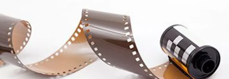 Carrete de película fotográfica desenrollado sobre fondo blanco.