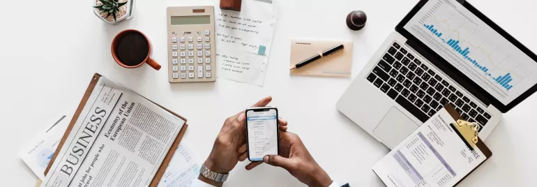 Mesa de trabajo con portátil, móvil y documentos.