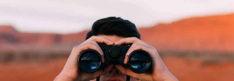 Persona observando con binoculares en un paisaje desértico.