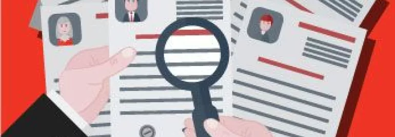 Manos sosteniendo una lupa sobre un currículum.