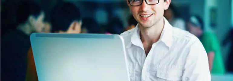 Persona sonriente trabajando en una computadora portátil en una cafetería.