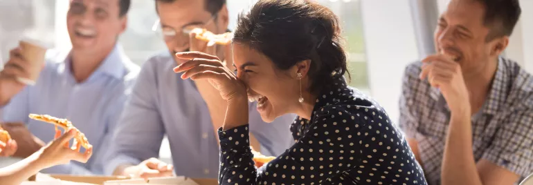 Grupo de personas riendo mientras comen pizza.