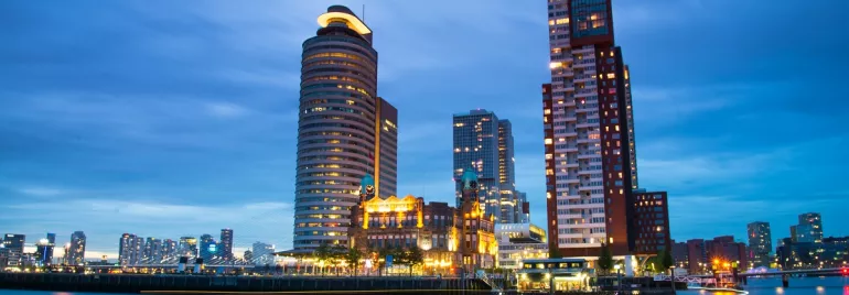 Vista nocturna de una ciudad moderna junto al río, con edificios iluminados.