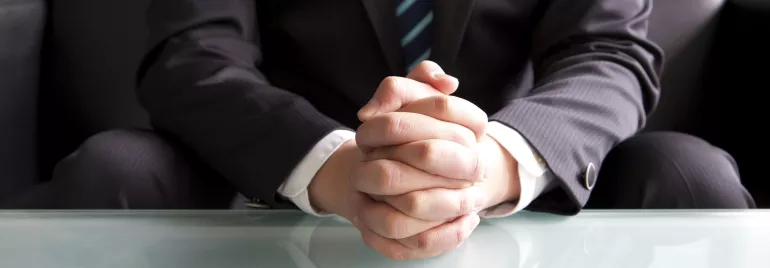 Persona con traje sentado detrás de una mesa.
