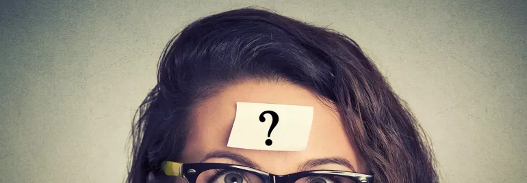 Persona con gafas y nota adhesiva con signo de interrogación en la frente.