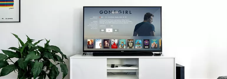 Televisor con película y catálogo de videos en una sala moderna.