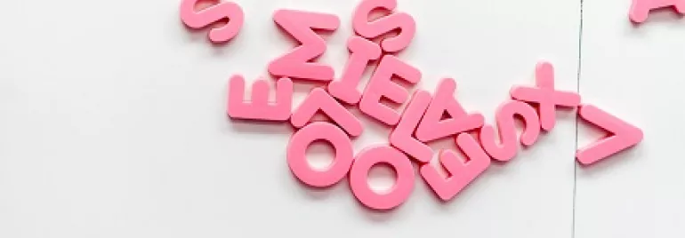 Letras rosadas dispersas sobre una superficie blanca.