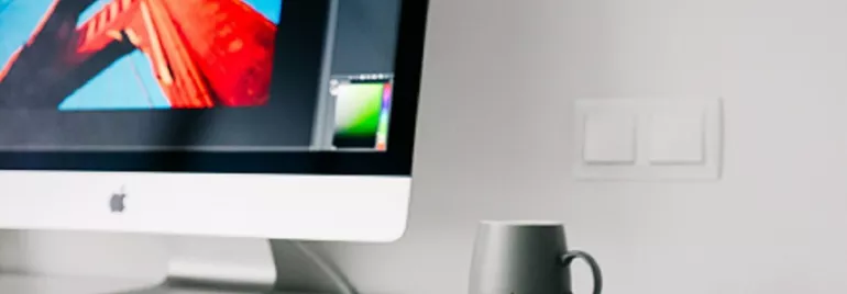 Escritorio con computadora, taza y gafas.