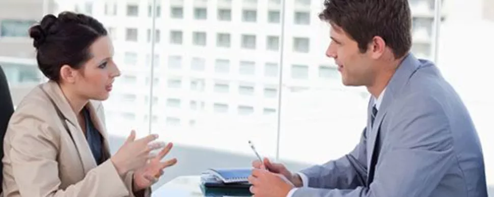 Dos personas hablando en una sala de juntas moderna.