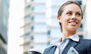 Persona sonriendo con traje, sosteniendo una taza y un periódico.