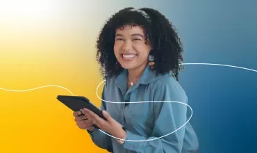 Persona sonriendo mientras sostiene una tableta, fondo amarillo y azul.
