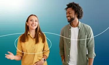 Dos personas sonríen frente a un fondo azul con líneas blancas.
